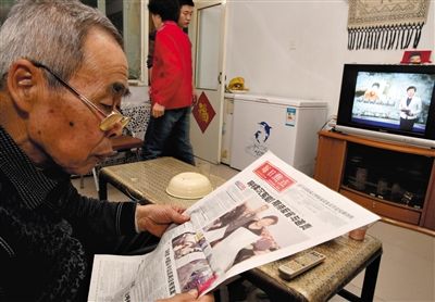  去年12月16日晚，呼格吉勒图的父亲李三仁在家中看新华每日电讯关于呼格案的整版报道。央视焦点访谈栏目刚好也在播放关于呼格案件的新闻。新京报记者 郭铁流 周岗峰 摄