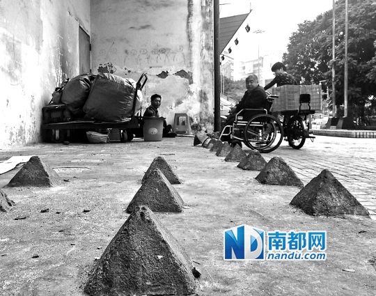 流浪汉安营在广州环市中路某营业厅外的水泥锥之间。