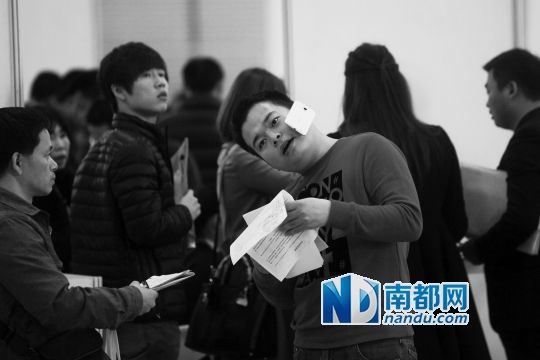 **窗口，一市民询问情况，双手都拿着资料，手机只能“搁”脸上。南都记者 王子荣 摄